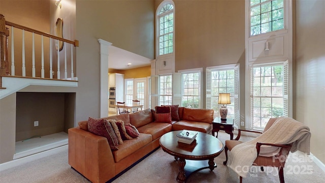 living area featuring baseboards, a high ceiling, and carpet flooring