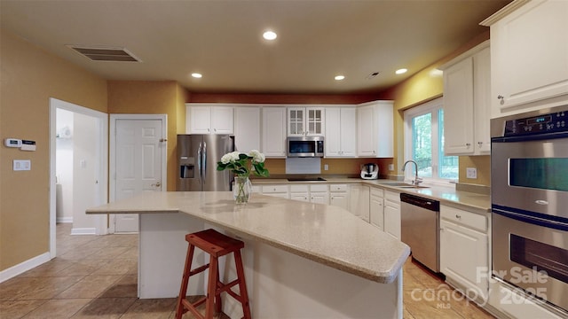 kitchen with a sink, visible vents, white cabinets, and stainless steel appliances