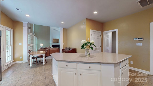 kitchen featuring white cabinets, visible vents, a kitchen island, and light tile patterned floors