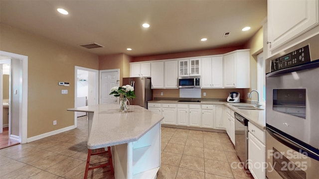 kitchen featuring a breakfast bar area, a sink, stainless steel appliances, and light countertops