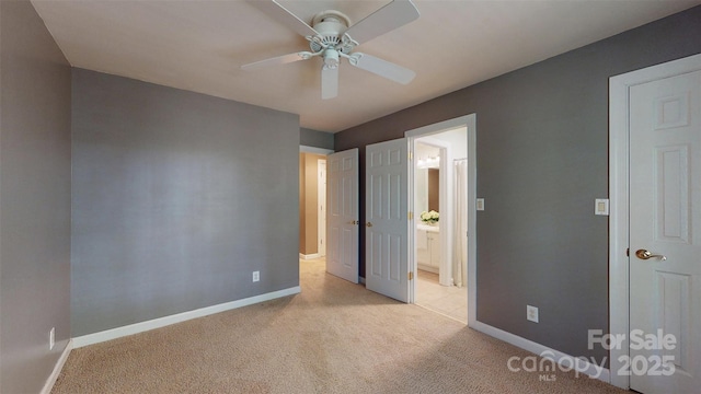 unfurnished bedroom featuring light colored carpet, baseboards, a ceiling fan, and ensuite bathroom