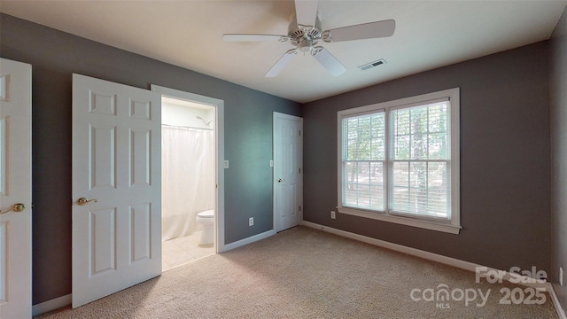unfurnished bedroom with light carpet, baseboards, visible vents, ceiling fan, and ensuite bath