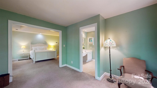 bedroom with baseboards, light carpet, and ensuite bathroom