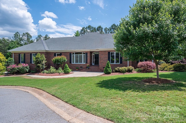 ranch-style house with brick siding, a front lawn, and roof with shingles