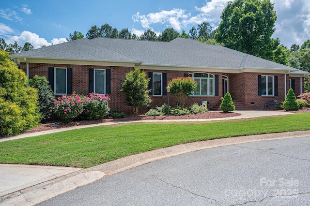 ranch-style home featuring brick siding, a front lawn, and a shingled roof