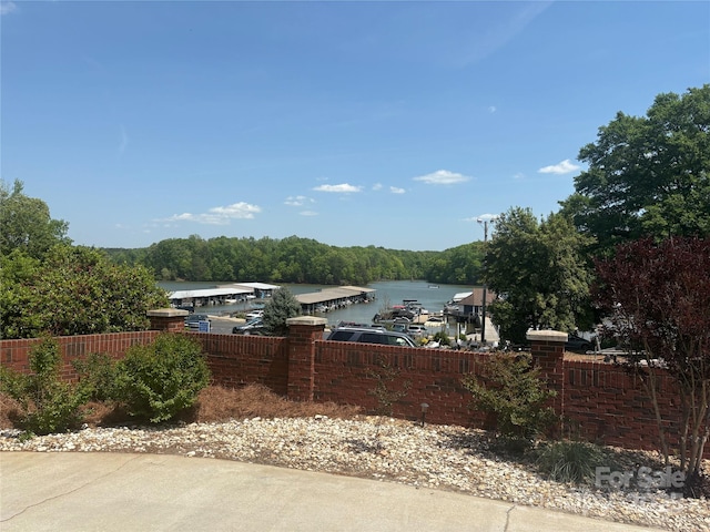 view of patio with fence, a wooded view, and a water view
