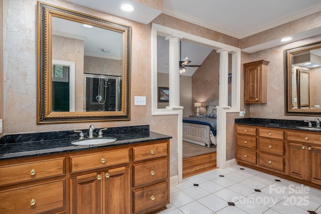 ensuite bathroom with decorative columns, crown molding, tile patterned floors, a stall shower, and two vanities