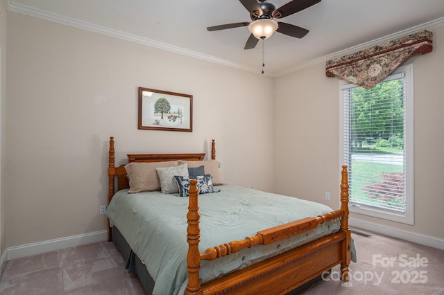 carpeted bedroom featuring baseboards, crown molding, and ceiling fan