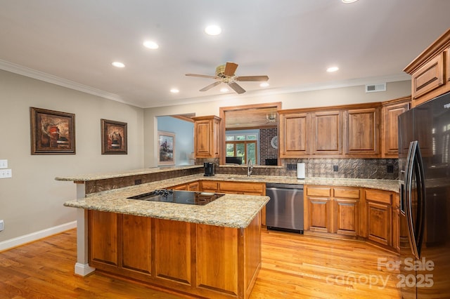 kitchen with black appliances, a sink, decorative backsplash, brown cabinetry, and ornamental molding