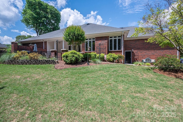 rear view of property featuring brick siding and a lawn