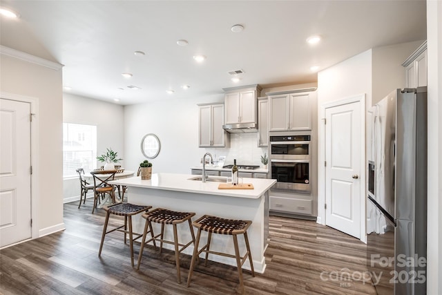 13210 Kenworth Rd, Charlotte, NC 28278 - kitchen with appliances with stainless steel finishes, dark wood-type flooring, decorative backsplash, a kitchen bar, and a center island with sink