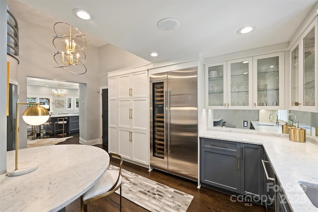 423 N Pine St, Charlotte, NC 28202 - kitchen with glass insert cabinets, white cabinets, built in fridge, light stone counters, and a notable chandelier