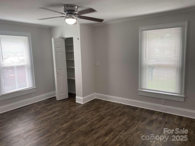 unfurnished bedroom with baseboards, ornamental molding, dark wood-style floors, and multiple windows