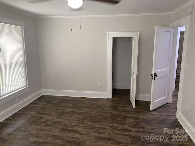 empty room with a ceiling fan, baseboards, dark wood-style floors, and ornamental molding