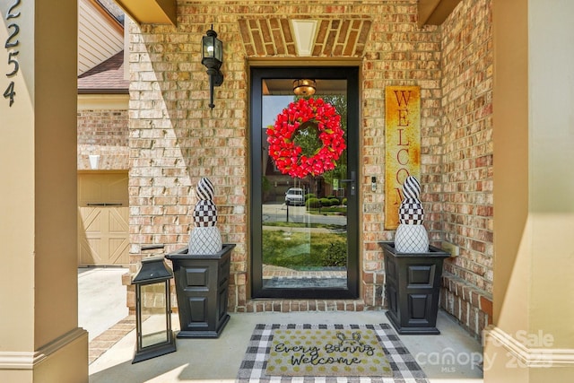 entrance to property featuring brick siding and roof with shingles