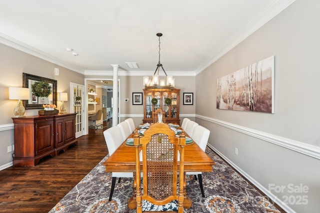 dining space featuring ornate columns, dark wood-style floors, ornamental molding, baseboards, and a notable chandelier