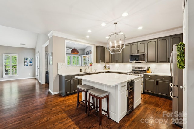 kitchen with a center island, a chandelier, stainless steel appliances, dark wood-type flooring, and wine cooler