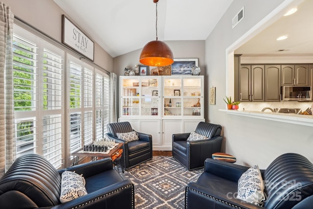 living room with vaulted ceiling, visible vents, and wood finished floors