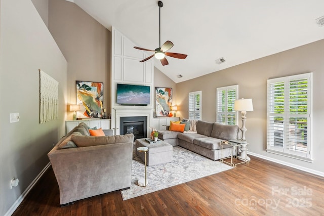 living area featuring visible vents, baseboards, a ceiling fan, wood finished floors, and high vaulted ceiling