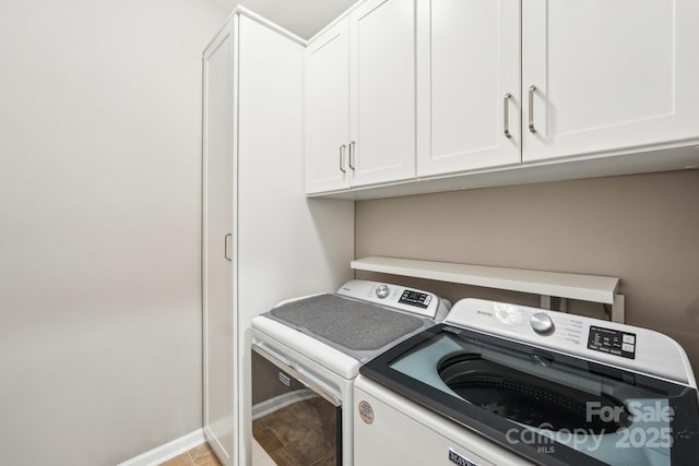 laundry area featuring washing machine and dryer, baseboards, and cabinet space