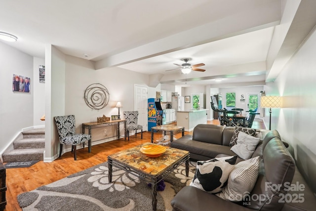 living area with light wood-style floors, stairs, a ceiling fan, and baseboards