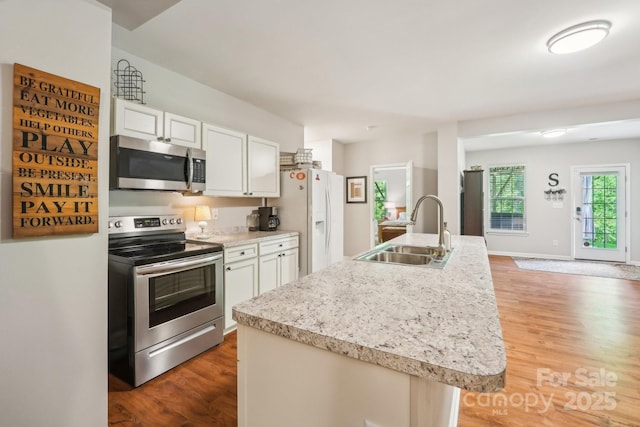 kitchen featuring white cabinets, light wood finished floors, light countertops, a sink, and appliances with stainless steel finishes