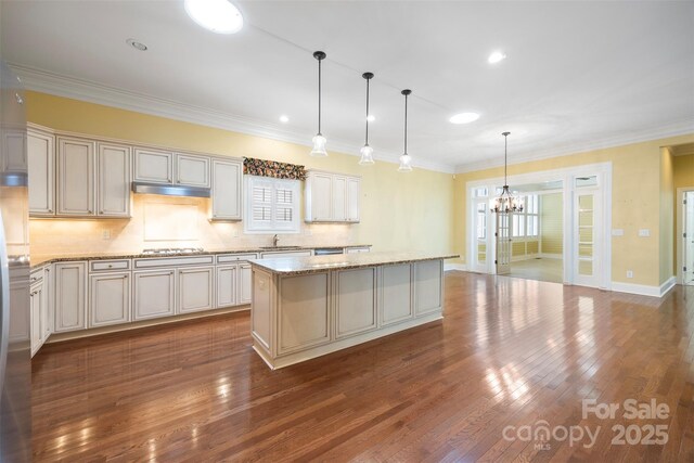 kitchen featuring a sink, dark wood finished floors, a notable chandelier, stainless steel gas stovetop, and a kitchen island