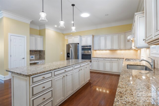 kitchen with a sink, backsplash, appliances with stainless steel finishes, light stone countertops, and a kitchen island