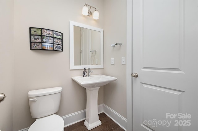 half bath featuring wood finished floors, baseboards, and toilet