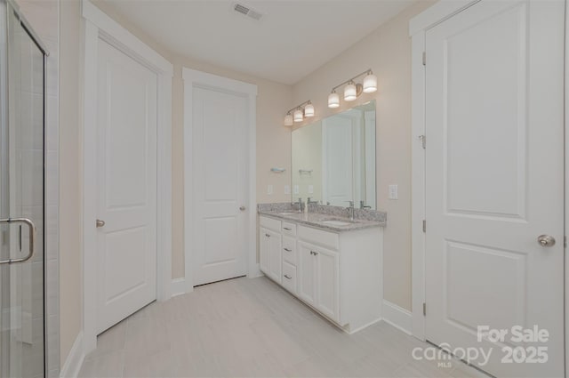 full bath featuring a sink, double vanity, baseboards, visible vents, and a shower stall