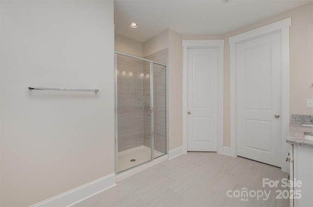 bathroom with recessed lighting, a shower stall, tile patterned flooring, vanity, and baseboards