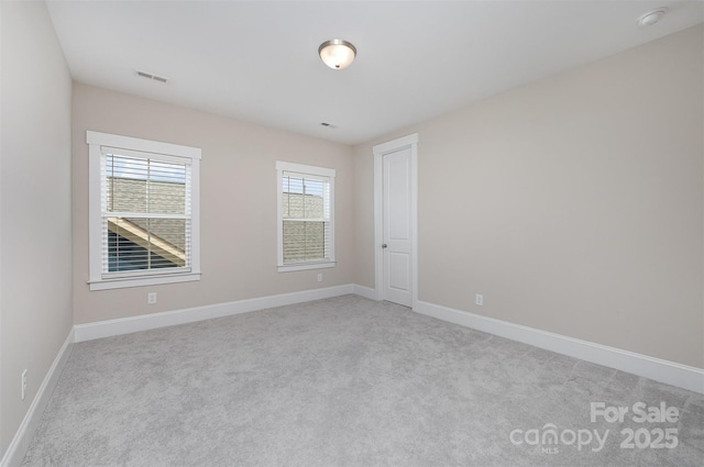 spare room featuring light carpet, visible vents, and baseboards
