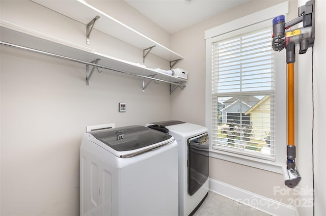 washroom featuring laundry area, light tile patterned flooring, a wealth of natural light, baseboards, and separate washer and dryer