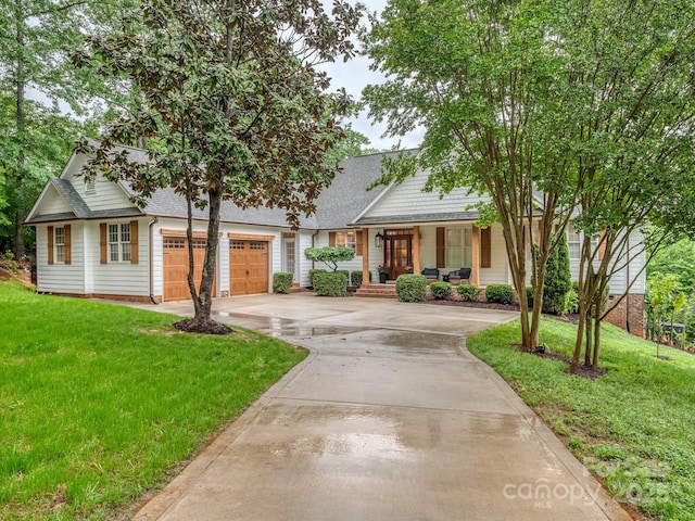 view of front facade with a porch, a front yard, concrete driveway, and roof with shingles