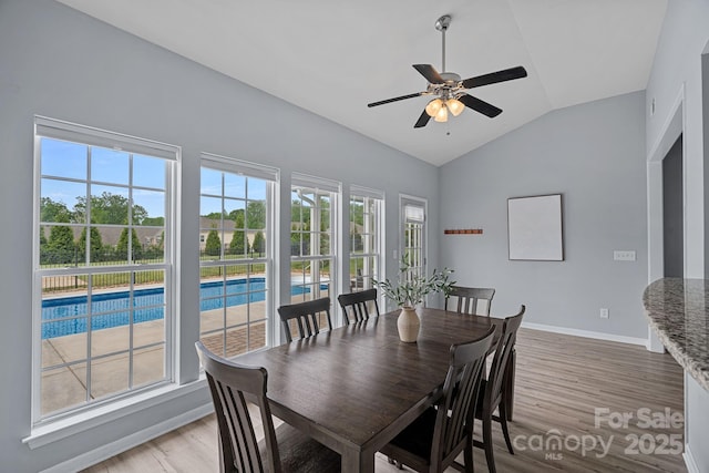 dining space featuring baseboards, vaulted ceiling, ceiling fan, and light wood-type flooring