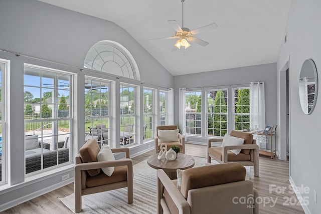 sunroom / solarium featuring wood finished floors, high vaulted ceiling, and a healthy amount of sunlight