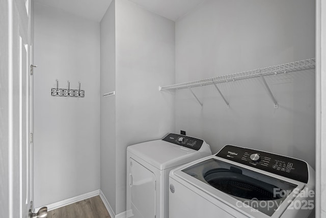 laundry area featuring baseboards, wood finished floors, laundry area, and independent washer and dryer