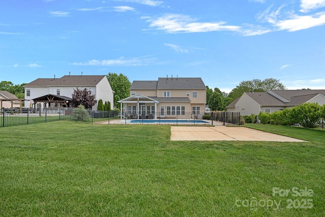 back of property with a lawn, a patio area, and a fenced in pool