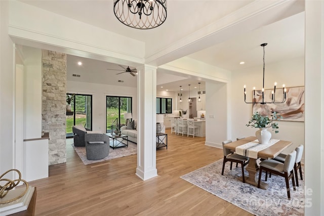 dining room with light wood finished floors, recessed lighting, decorative columns, visible vents, and ceiling fan with notable chandelier