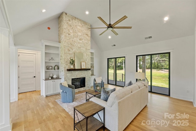 living area with light wood finished floors, visible vents, ceiling fan, and high vaulted ceiling