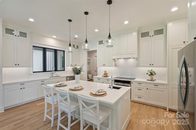 kitchen featuring backsplash, a sink, appliances with stainless steel finishes, and a center island with sink