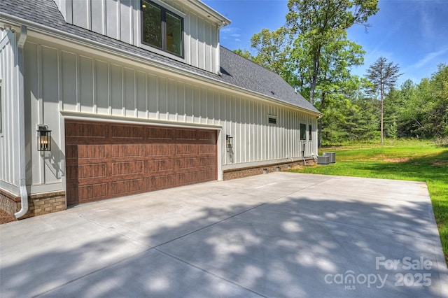 view of home's exterior featuring a yard, an attached garage, board and batten siding, and roof with shingles