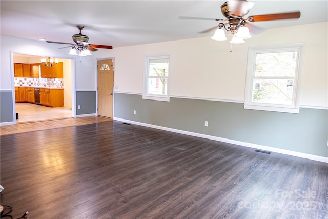 unfurnished living room featuring visible vents, baseboards, light wood-style floors, and ceiling fan with notable chandelier