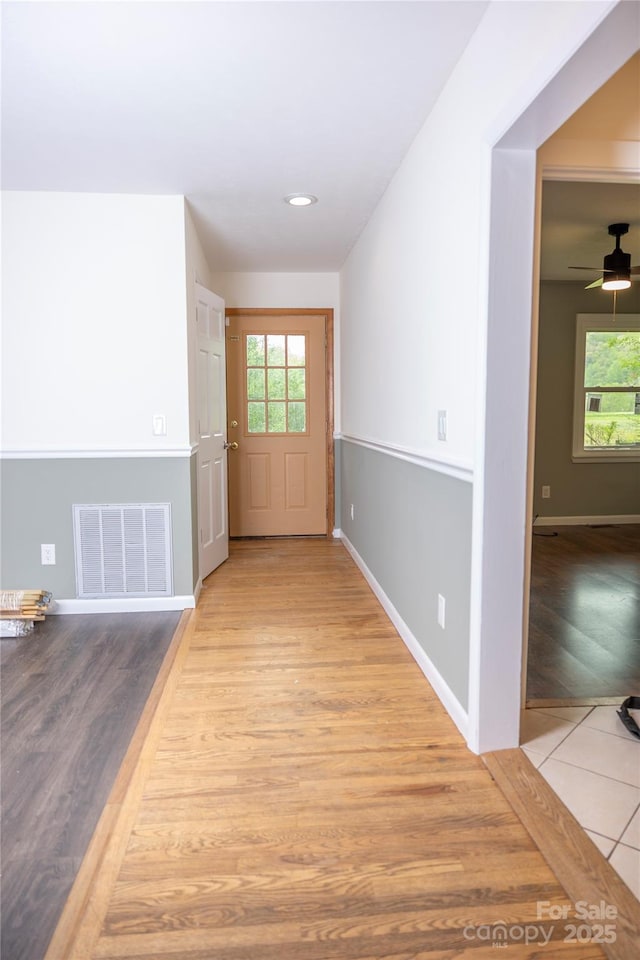 unfurnished room with baseboards, visible vents, wood finished floors, and plenty of natural light