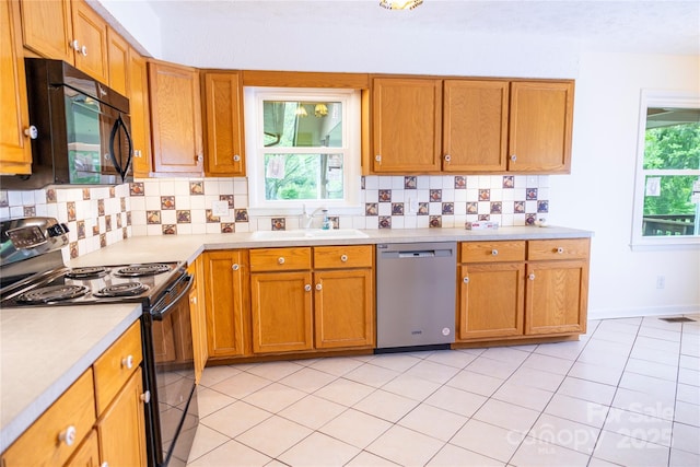 kitchen with brown cabinets, a sink, black appliances, backsplash, and light countertops
