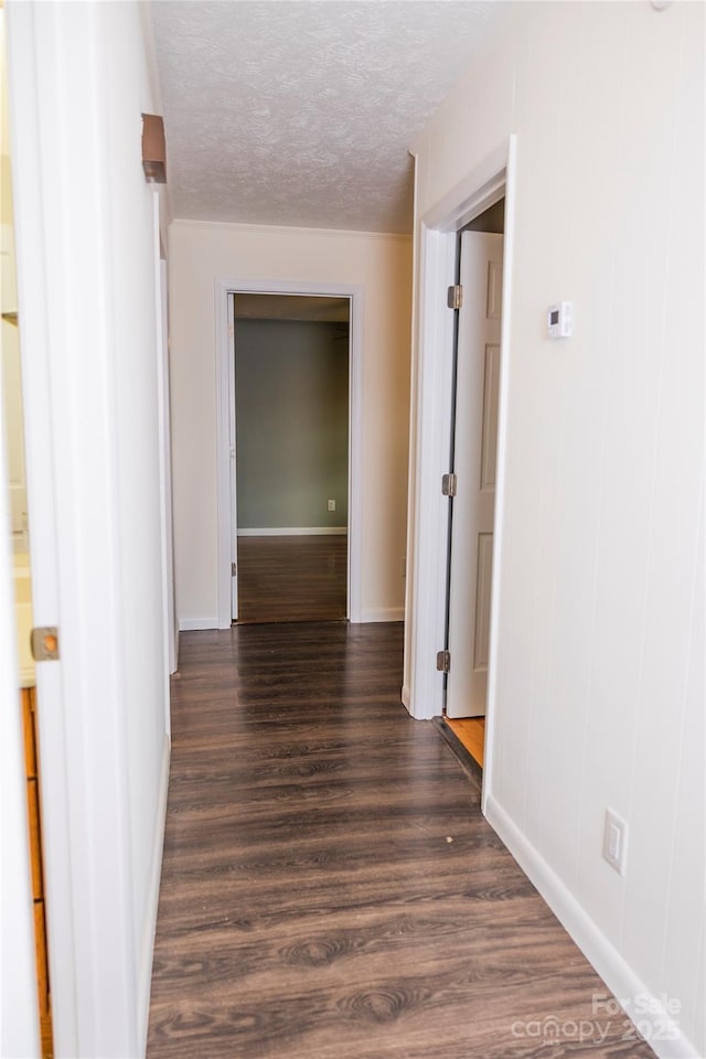 hall featuring baseboards, a textured ceiling, and dark wood-style flooring