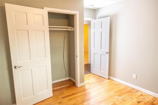 unfurnished bedroom with a closet, baseboards, and light wood-style floors