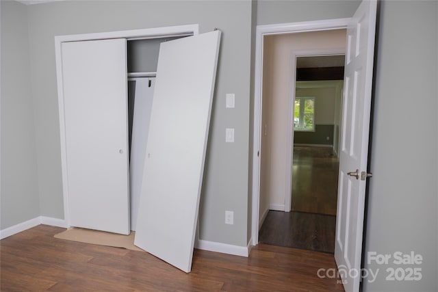 unfurnished bedroom featuring wood finished floors, a closet, and baseboards