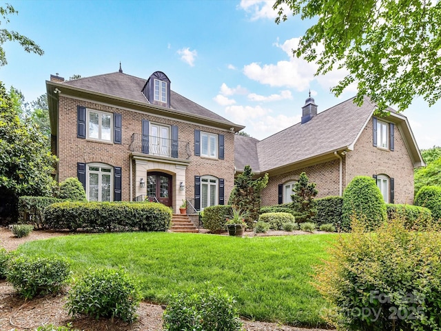 colonial home featuring a chimney, a front yard, and brick siding
