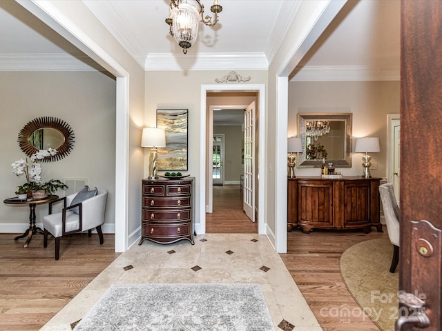 hall featuring an inviting chandelier, ornamental molding, visible vents, wood finished floors, and baseboards